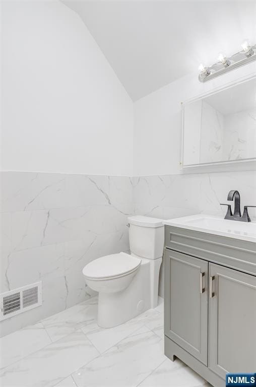 85 Myrtle Ave, Jersey City, NJ 07305 - bathroom with marble finish floors, tile walls, toilet, vanity, and lofted ceiling