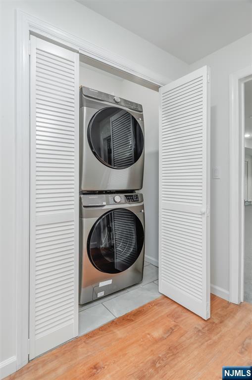 85 Myrtle Ave, Jersey City, NJ 07305 - laundry area featuring stacked washing machine and dryer, baseboards, and wood finished floors