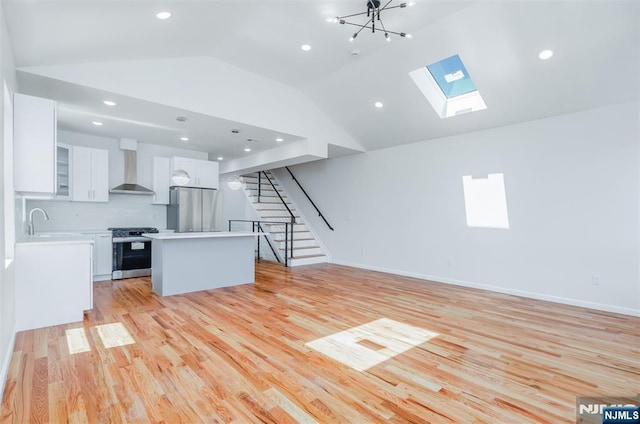 85 Myrtle Ave, Jersey City, NJ 07305 - unfurnished living room featuring vaulted ceiling, stairway, a skylight, light wood-style floors, and recessed lighting