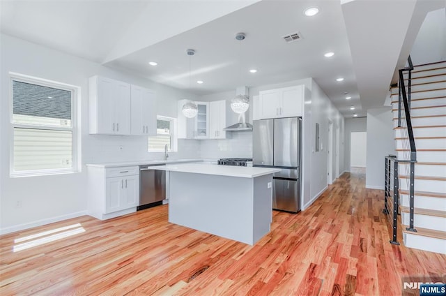 85 Myrtle Ave, Jersey City, NJ 07305 - kitchen with appliances with stainless steel finishes, light wood-type flooring, a kitchen island, light countertops, and white cabinets