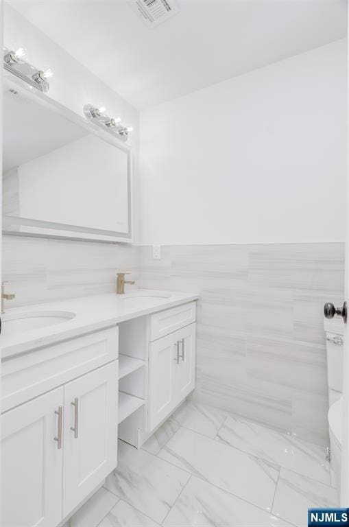 85 Myrtle Ave, Jersey City, NJ 07305 - full bathroom with double vanity, marble look tile flooring, and wainscoting