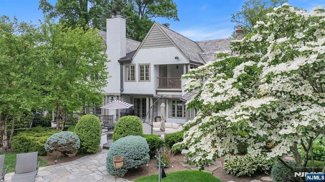 76 Wildwood Rd, Ridgewood, NJ 07450 - view of front of home with a balcony, a chimney, a patio area, and stucco siding