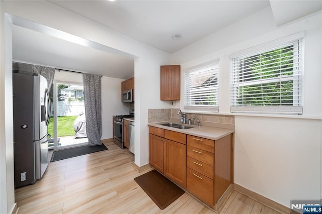 1096 Stasia St, Teaneck, NJ 07666 - kitchen with stainless steel appliances, a sink, brown cabinetry, light countertops, and light wood-type flooring