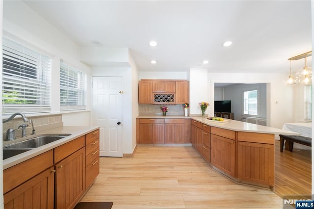 1096 Stasia St, Teaneck, NJ 07666 - kitchen with a sink, light wood-style flooring, decorative backsplash, a peninsula, and light countertops