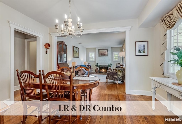 640 E Glen Ave, Ridgewood, NJ 07450 - dining space featuring wood finished floors, a chandelier, a brick fireplace, and baseboards