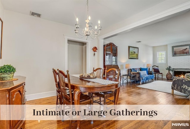 640 E Glen Ave, Ridgewood, NJ 07450 - dining area with light wood finished floors, a chandelier, baseboards, and a brick fireplace