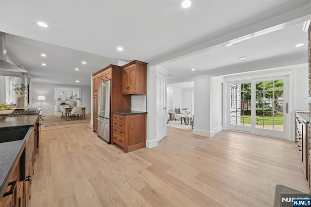 249 Valley Rd, Montclair, NJ 07042 - kitchen featuring freestanding refrigerator, dark countertops, brown cabinetry, wall chimney range hood, and light wood-style floors