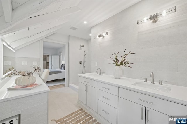 249 Valley Rd, Montclair, NJ 07042 - ensuite bathroom featuring double vanity, tile walls, tile patterned floors, and vaulted ceiling