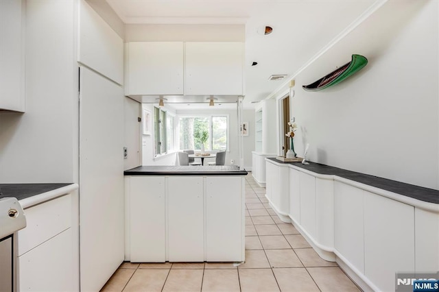 60 Leach Dr, Bloomingdale, NJ 07403 - kitchen with light tile patterned floors, white cabinetry, dark countertops, and crown molding