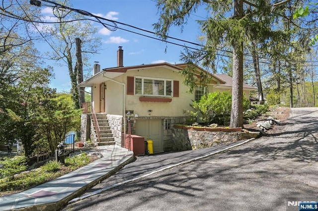 60 Leach Dr, Bloomingdale, NJ 07403 - view of front of home with a chimney, stairs, stone siding, and stucco siding
