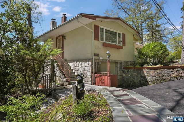 60 Leach Dr, Bloomingdale, NJ 07403 - view of front of property featuring stone siding, a chimney, stairway, and stucco siding