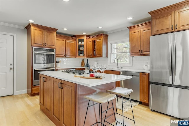 61 Ferndale Rd, Paramus, NJ 07652 - kitchen featuring stainless steel appliances, a sink, brown cabinets, ornamental molding, and light wood-type flooring