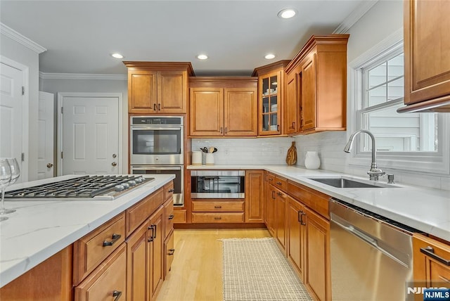 61 Ferndale Rd, Paramus, NJ 07652 - kitchen with stainless steel appliances, a sink, crown molding, light wood-style floors, and brown cabinets