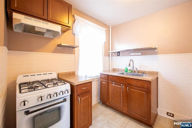 65 Byrne St, Hackensack, NJ 07601 - kitchen with white gas stove, under cabinet range hood, a sink, open shelves, and brown cabinets