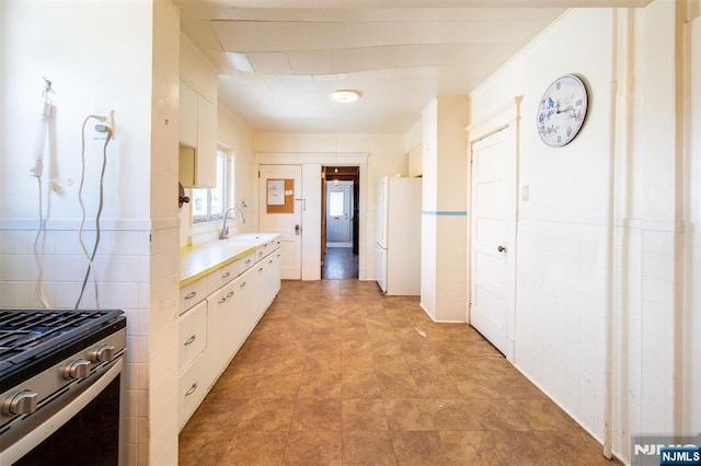 65 Byrne St, Hackensack, NJ 07601 - kitchen with freestanding refrigerator, light countertops, a sink, white cabinets, and stainless steel range with gas stovetop
