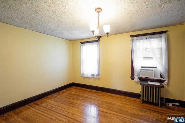 65 Byrne St, Hackensack, NJ 07601 - spare room with radiator, a chandelier, hardwood / wood-style flooring, baseboards, and a textured ceiling