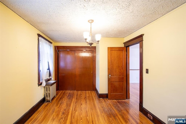 65 Byrne St, Hackensack, NJ 07601 - hallway featuring wood finished floors, a chandelier, radiator heating unit, a textured ceiling, and baseboards