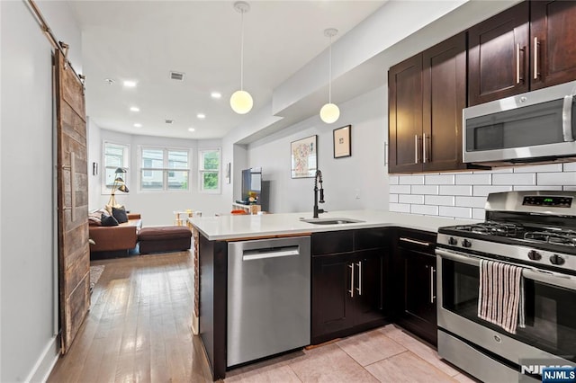 172 S St Unit 2A, Jersey City, NJ 07307 - kitchen featuring stainless steel appliances, a sink, open floor plan, a peninsula, and light countertops