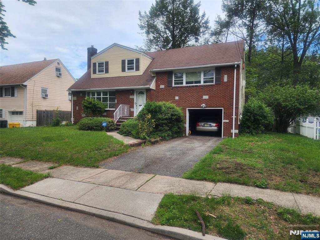 107 Irvington, Teaneck, NJ 07666 - tri-level home featuring brick siding, a chimney, asphalt driveway, and an attached garage