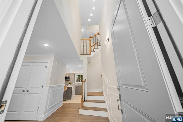 16 Coles Ct, River Edge, NJ 07661 - foyer entrance featuring stairway, light wood-type flooring, ornamental molding, wainscoting, and a decorative wall