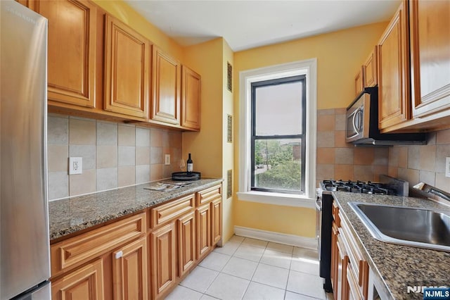 50 Reservoir Ave Unit 201, Jersey City, NJ 07307 - kitchen with stainless steel appliances, light tile patterned flooring, baseboards, dark stone counters, and backsplash