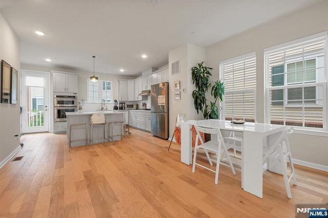 83 Landmark Ln, Fair Lawn, NJ 07410 - kitchen featuring stainless steel appliances, light wood finished floors, a kitchen bar, baseboards, and a center island