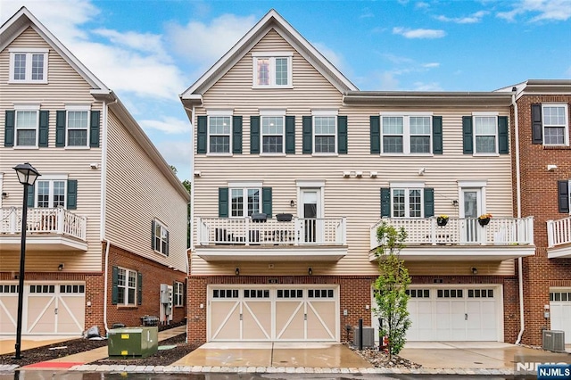 83 Landmark Ln, Fair Lawn, NJ 07410 - rear view of house with central AC unit, an attached garage, and brick siding