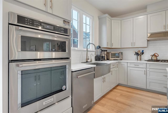 83 Landmark Ln, Fair Lawn, NJ 07410 - kitchen featuring stainless steel appliances, backsplash, light countertops, and light wood-style floors