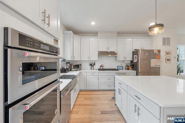 83 Landmark Ln, Fair Lawn, NJ 07410 - kitchen featuring stainless steel appliances, under cabinet range hood, light countertops, tasteful backsplash, and recessed lighting