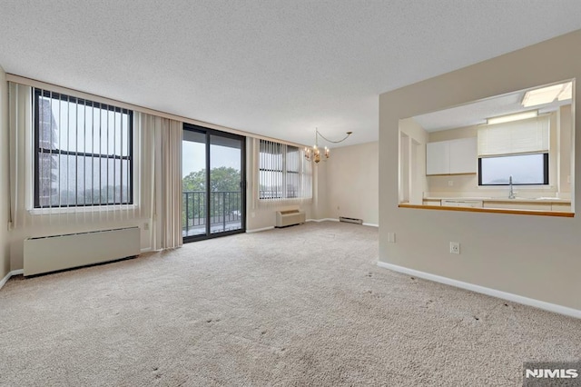 200 Division Unit 6H, Cliffside Park, NJ 07010 - unfurnished living room with a chandelier, light carpet, a sink, baseboards, and a textured ceiling