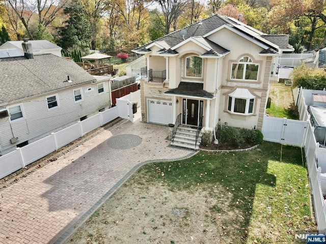 238 E Johnson Ave, Bergenfield, NJ 07621 - view of front of house featuring a gate, stucco siding, roof mounted solar panels, roof with shingles, and an attached garage