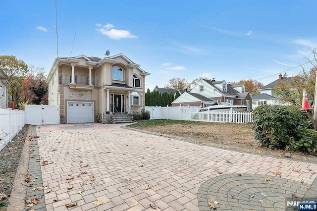 238 E Johnson Ave, Bergenfield, NJ 07621 - traditional home with a balcony, a garage, stone siding, a gate, and decorative driveway