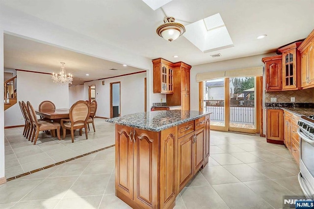 238 E Johnson Ave, Bergenfield, NJ 07621 - kitchen with a skylight, a chandelier, brown cabinets, light tile patterned flooring, and glass insert cabinets