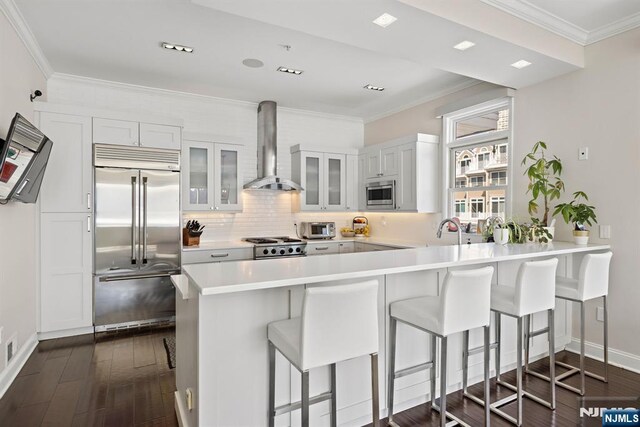 443 Albany Ct Unit 443, West New York, NJ 07093 - kitchen with built in appliances, wall chimney exhaust hood, a kitchen bar, a peninsula, and glass insert cabinets