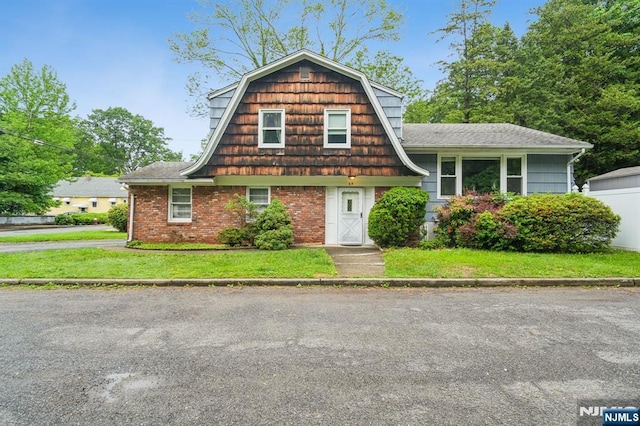 69 Bogert Pl, Bergenfield, NJ 07621 - view of front of property with a front yard, a gambrel roof, and brick siding
