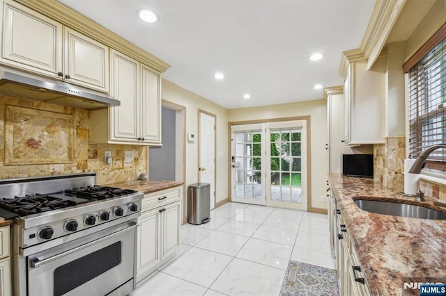 24 Willet, Bloomfield, NJ 07003 - kitchen featuring stainless steel range with gas cooktop, a sink, baseboards, cream cabinets, and under cabinet range hood
