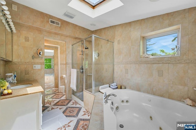 21 Sheridan Ave, West Orange, NJ 07052 - bathroom with tile walls, a skylight, a stall shower, a whirlpool tub, and vanity