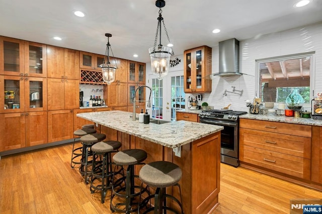 21 Sheridan Ave, West Orange, NJ 07052 - kitchen featuring stainless steel gas range, wall chimney exhaust hood, brown cabinetry, light wood-style flooring, and recessed lighting