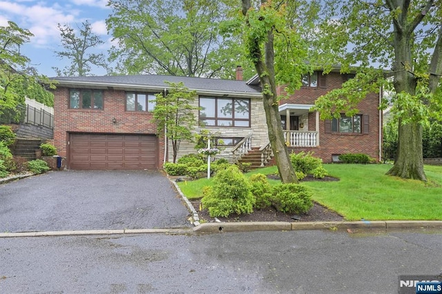 379 Mauro Rd, Englewood Cliffs, NJ 07632 - view of front facade featuring brick siding, an attached garage, asphalt driveway, a front yard, and a chimney