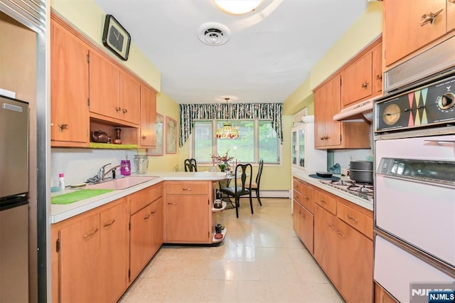 379 Mauro Rd, Englewood Cliffs, NJ 07632 - kitchen with white oven, light countertops, a peninsula, under cabinet range hood, and light tile patterned floors