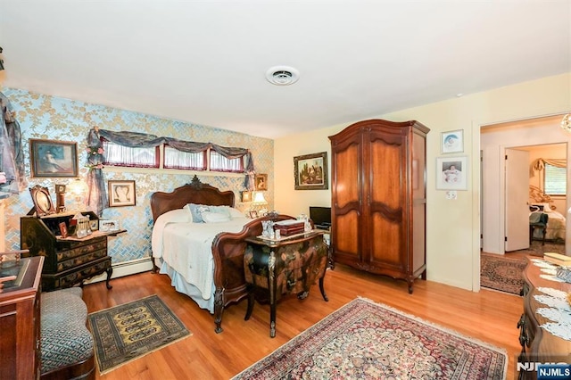379 Mauro Rd, Englewood Cliffs, NJ 07632 - bedroom with wallpapered walls, light wood-style floors, multiple windows, a baseboard heating unit, and an accent wall