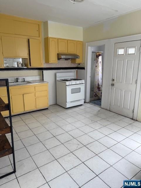 457 7th St, Newark, NJ 07107 - kitchen featuring white gas stove, under cabinet range hood, light brown cabinets, a sink, and light countertops