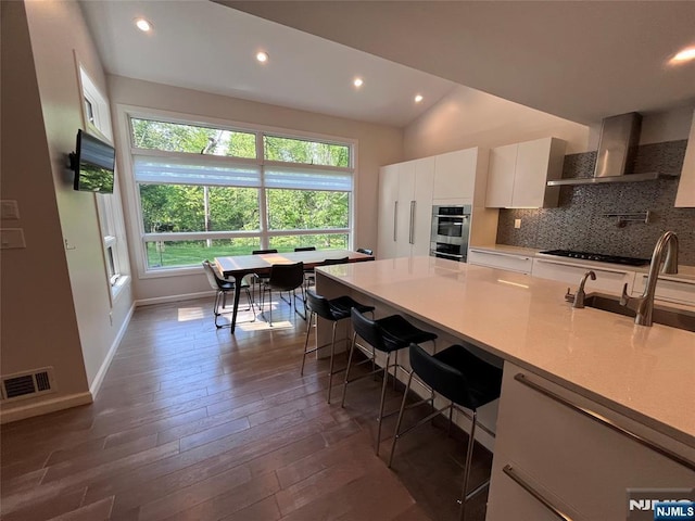 625 Roberge Dr, River Vale, NJ 07675 - kitchen with wall chimney exhaust hood, dark wood-type flooring, a breakfast bar, tasteful backsplash, and a sink