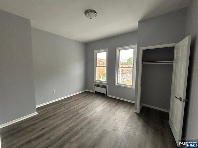 207 Tremont Ave, East Orange, NJ 07018 - unfurnished bedroom with radiator, dark wood finished floors, baseboards, and a closet