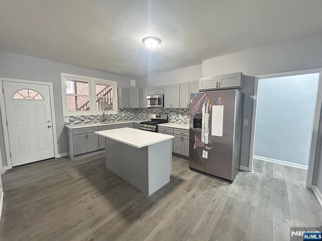 207 Tremont Ave, East Orange, NJ 07018 - kitchen featuring appliances with stainless steel finishes, gray cabinetry, a sink, wood finished floors, and backsplash