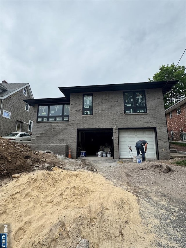 1087 Kingsland Ln, Fort Lee, NJ 07024 - view of home's exterior with a garage, brick siding, and dirt driveway