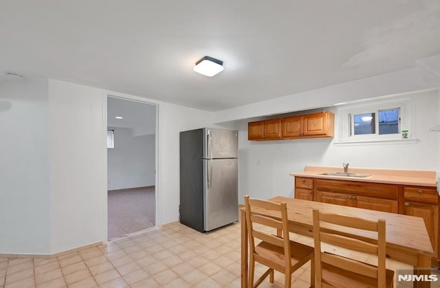 497 Oakdene Ave, Ridgefield, NJ 07657 - kitchen with freestanding refrigerator, a sink, brown cabinetry, light flooring, and light countertops