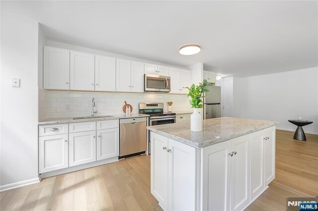 100 Grand Cove Way Unit 2D, Edgewater, NJ 07020 - kitchen with appliances with stainless steel finishes, a sink, light wood-style floors, and white cabinets