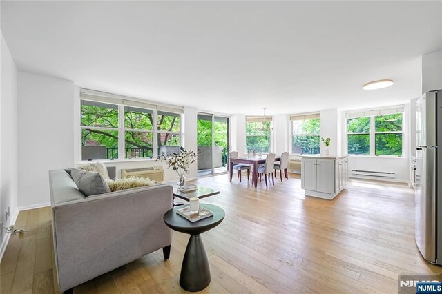 100 Grand Cove Way Unit 2D, Edgewater, NJ 07020 - living room featuring baseboard heating, light wood-style floors, and baseboards