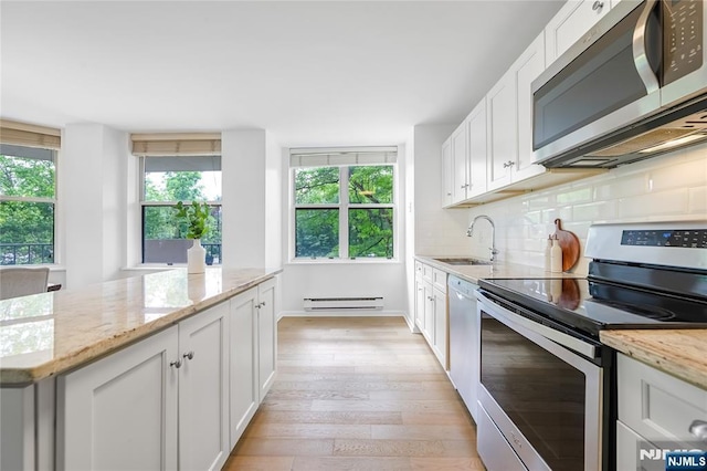 100 Grand Cove Way Unit 2D, Edgewater, NJ 07020 - kitchen with appliances with stainless steel finishes, a sink, a baseboard radiator, light wood-style flooring, and white cabinets